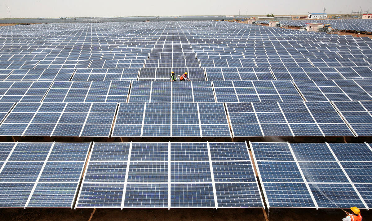Workers install photovoltaic solar panels at the Gujarat solar park under construction in Charanka village in Patan district of Gujarat. REUTERS file photo