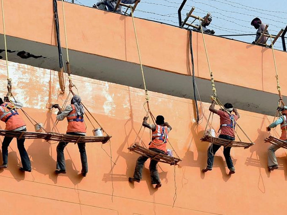 Workers paint the Secretariat Annexe building in saffron in Lucknow on Tuesday. PTI file photo .