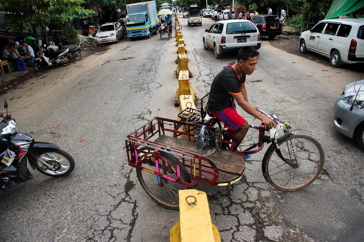 This photo taken on August 17, 2017 shows a trishaw driver making a turn on a street of Yangon. There are some 25,000 licensed drivers of the pedal-powered three-wheeler