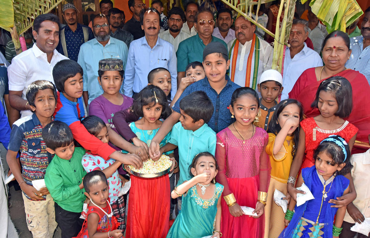 Children being distributed 'ellu-bella' on the occasion Makara Sankranti at Sri Rama Mandira, Devaraja Mohalla, in Mysuru on Monday. MLA Vasu and Corporator P Prashanth Gowda are seen.