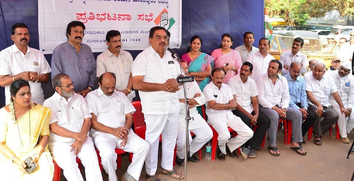 District -In-Charge Minister B Ramanath Rai addresses the protesters in front of DC's office in Mangaluru on Tuesday.