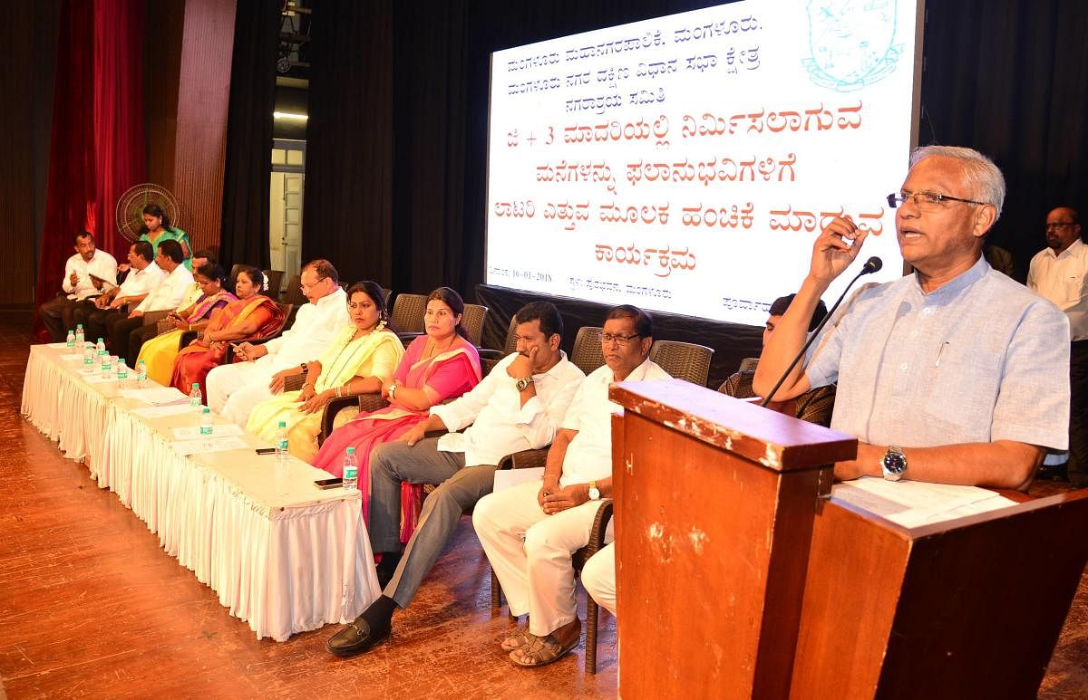 MLA J R Lobo speaks at a programme organised to allot flats to beneficiaries by picking lottery at Town Hall in Mangaluru on Tuesday.