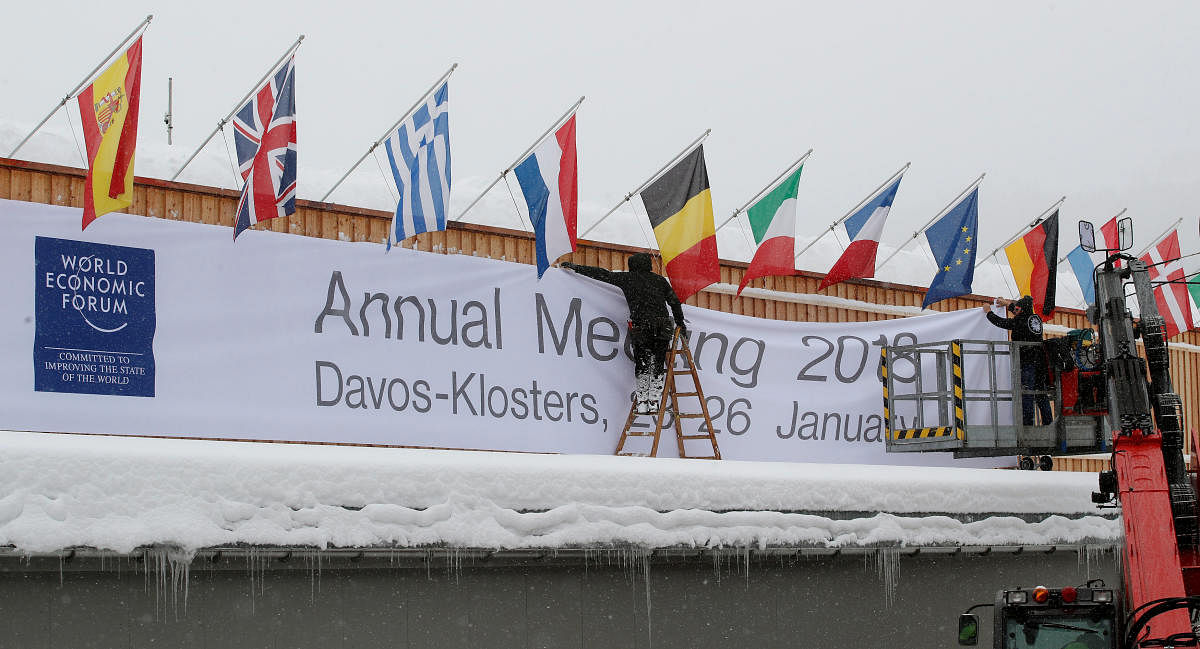 Workers fix a banner on the frontage of the congress centre, the venue of the upcoming World Economic Forum (WEF) in the Swiss mountain resort of Davos, Switzerland, January 18, 2018.