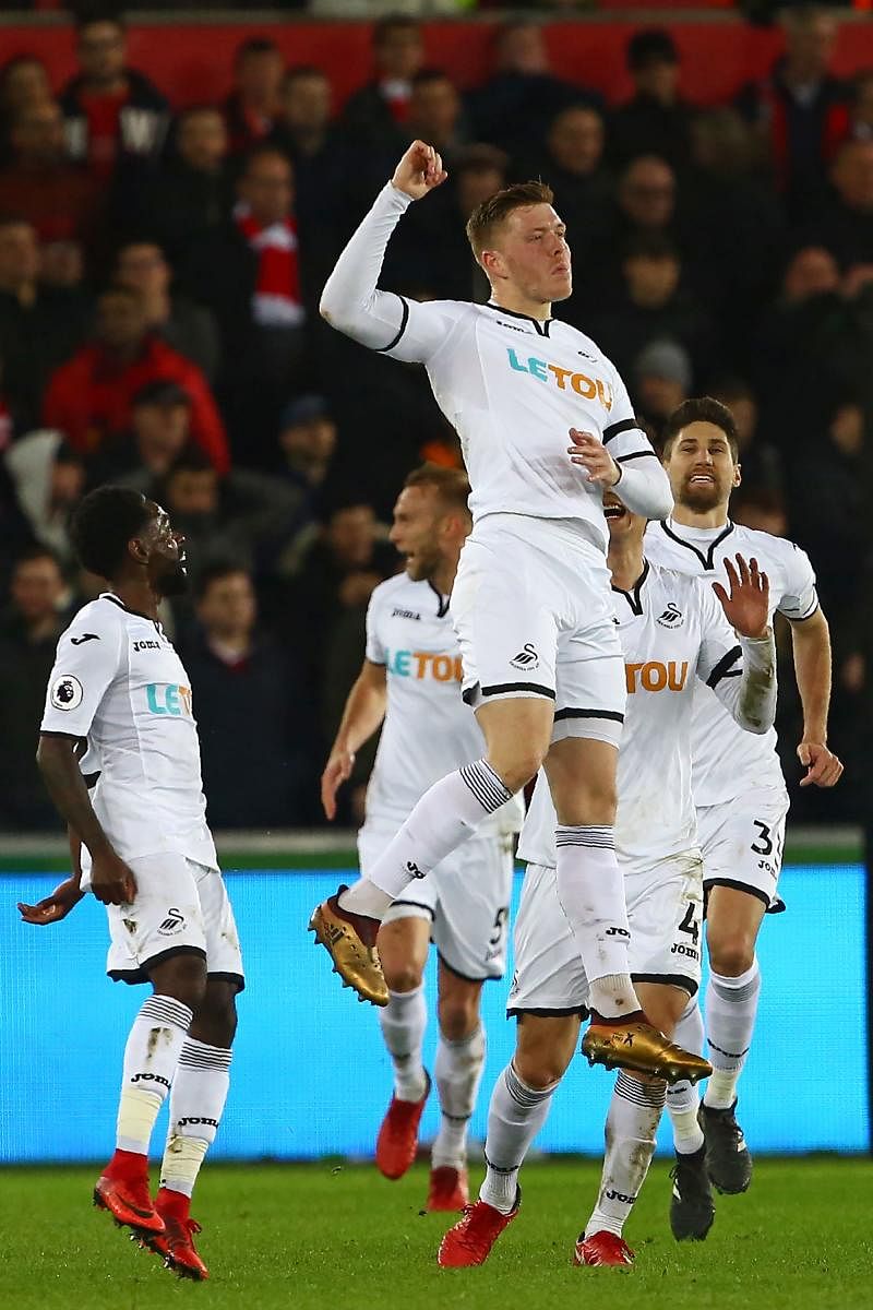 Determined: Swansea City's Alfie Mawson (centre) celebrates after scoring against Liverpool at The Liberty Stadium in Swansea on Monday. AFP