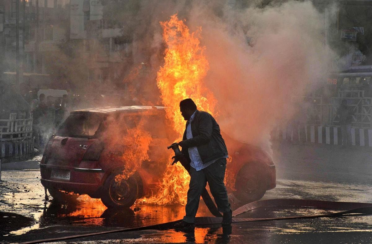 A firefighter tries to douse flames after Karni Sena workers torched a car during a demonstration against the release of 'Padmaavat' in Bhopal on Wednesday. PTI