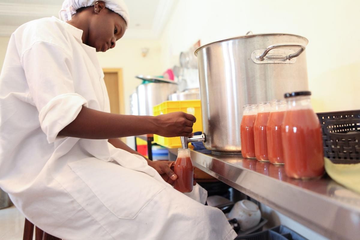 An employee of Zabbaan Holding, fills a bottle of juice made in Mali and all-natural, in Bamako, on October 13, 2017. Aissata Diakite's juices are part of an all-natural health startup which the 28-year-old Malian launched in December, blending traditional flavours with an engineer's eye for detail. The idea of launching a range of entirely natural fruit juices using locally sourced products from the African savannah came from her childhood in Mopti, a region in central Mali through which the Niger River flows. The business takes its name from the zaban -- or saba senegalensis, a shrub-like tree native to the Sahel region which grows predominantly on riverbanks and in woodlands, whose fruit and leaves are highly prized. / AFP PHOTO