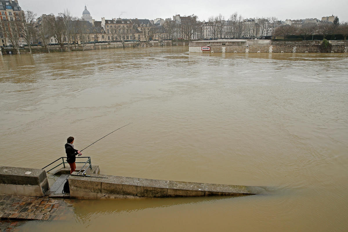 A man fishes on the flooded banks of the River Seine in Paris, France, on Saturday. REUTERS