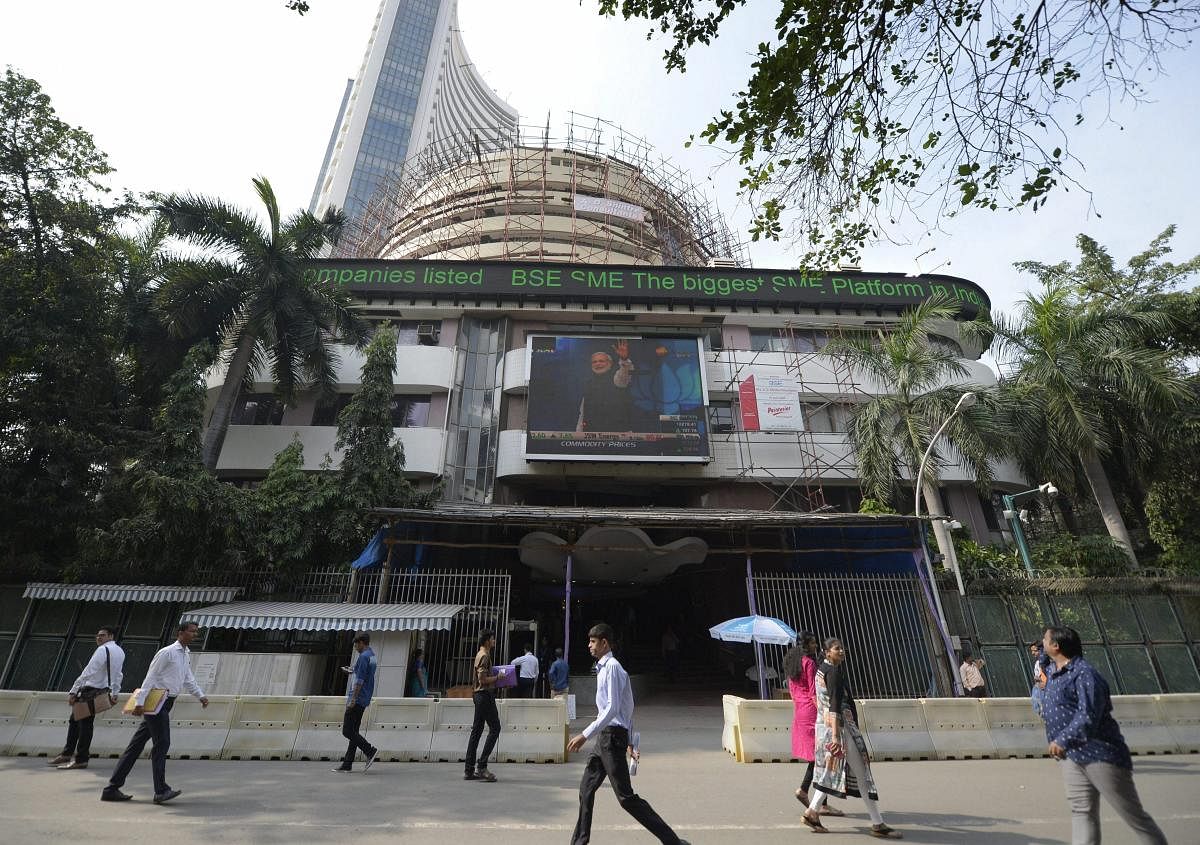 Mumbai: People look at a screen displaying Prime Minister Narendra Modi at the facade of the Bombay Stock Exchange in Mumbai on Monday. The BSE index Sensex soared on Monday follwing the BJP's victory in the Gujarat and HP Assembly polls. PTI Photo by Shashank Parade (PTI12_18_2017_000149B)