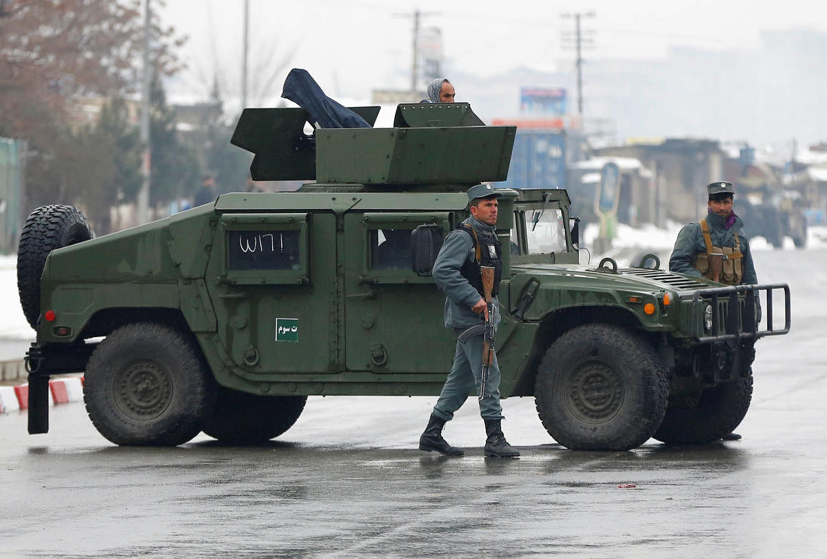 Afghan policemen keep watch near the site of an attack at the Marshal Fahim military academy in Kabul, Afghanistan
