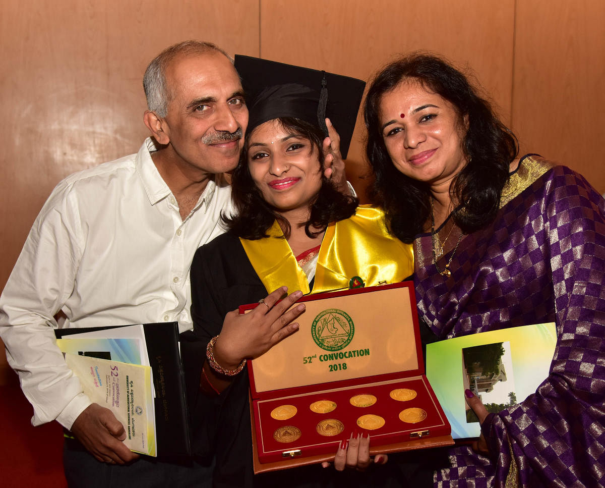 Winner of 8 gold medals and 5 gold certificate Sahana Bhat, BSc (Agriculture) of University of Agricultural Science, Bengaluru (UAS), sharing her joys with her parents Prakash Madguni and Sarita Bhat, during the 52nd convocation of University of Agricultural Sciences at GKVK in Bengaluru on Friday. Photo/ B H Shivakumar