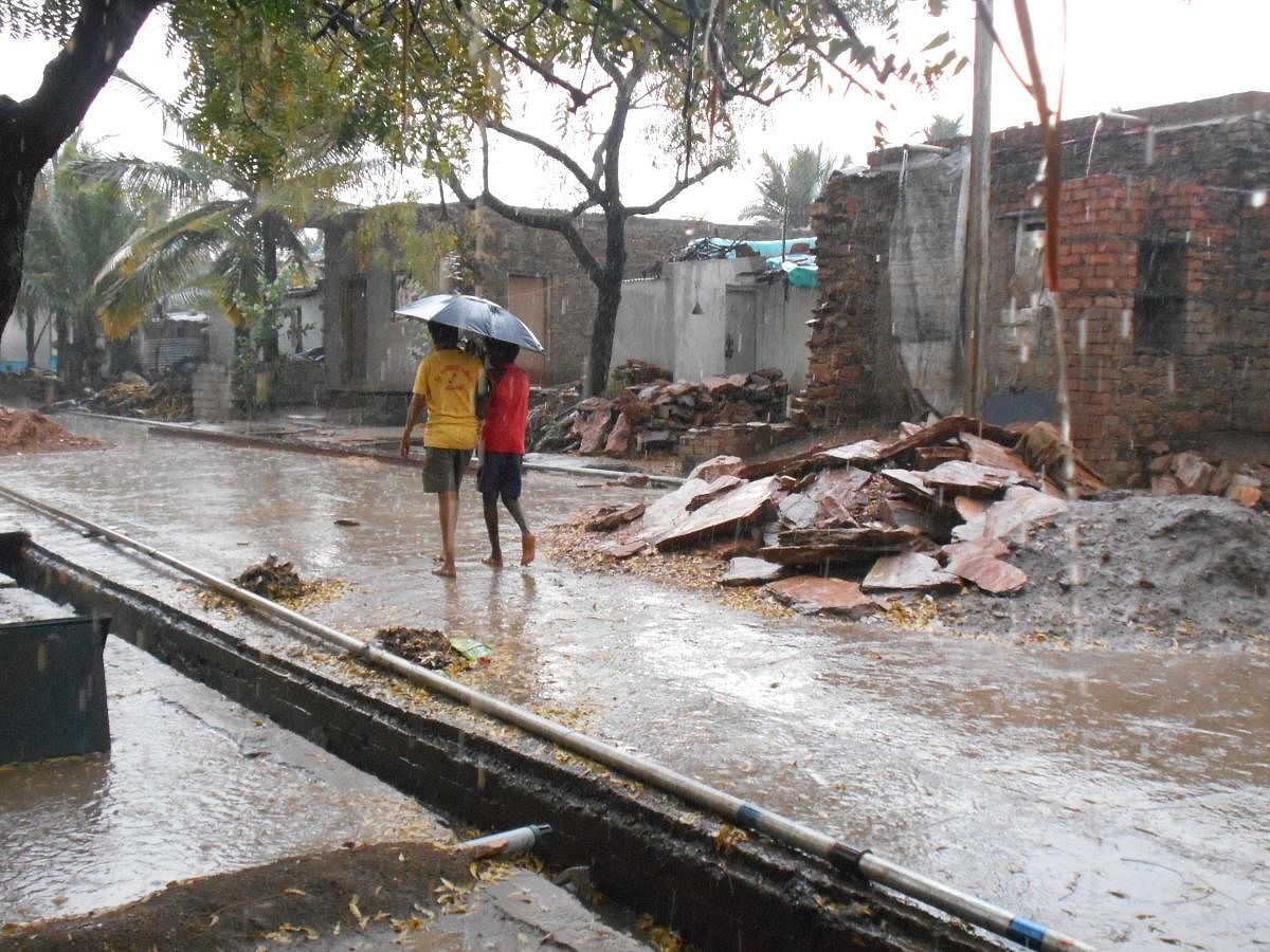 Boys take shelter under an umbrella during rain that lashed Dambal near Gadag on Sunday. dh photo