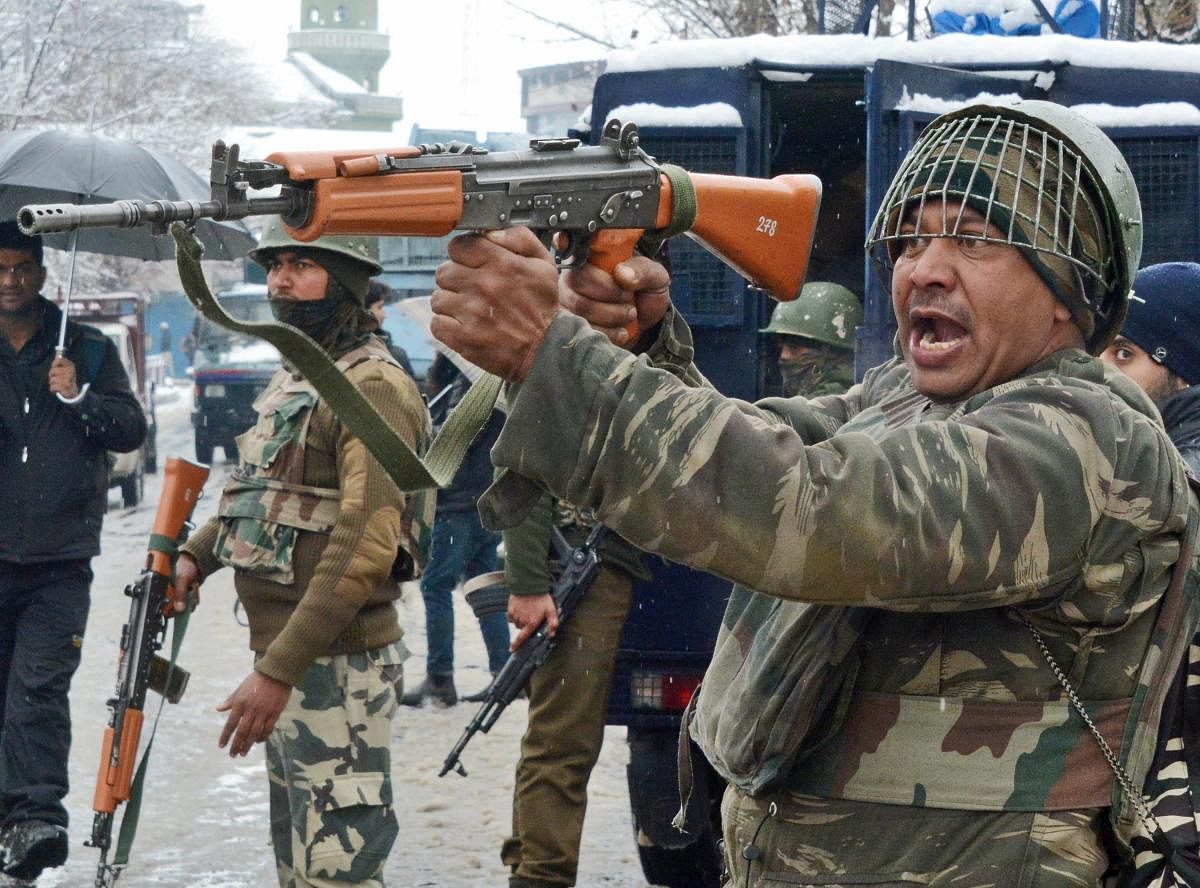 Security personnel take positions during an encounter with militants at Karra Nagar in Srinagar on Monday. PTI