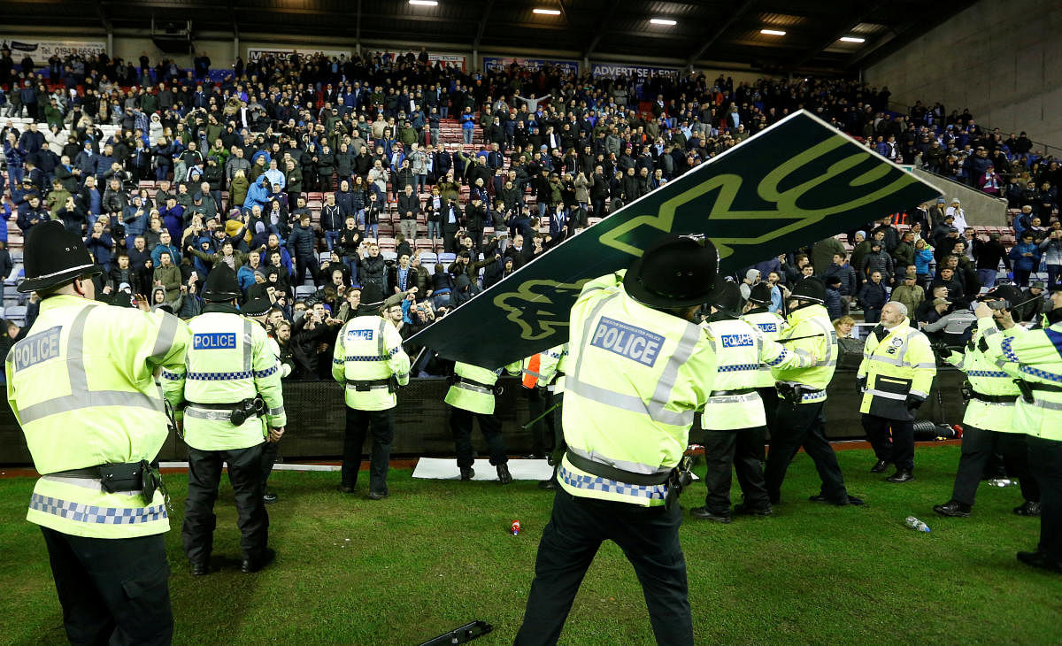 DISGRACEFUL Manchester City fans throw advertising hoarding as they clash with police officers after the match against Wigan Athletic on Monday. Reuters