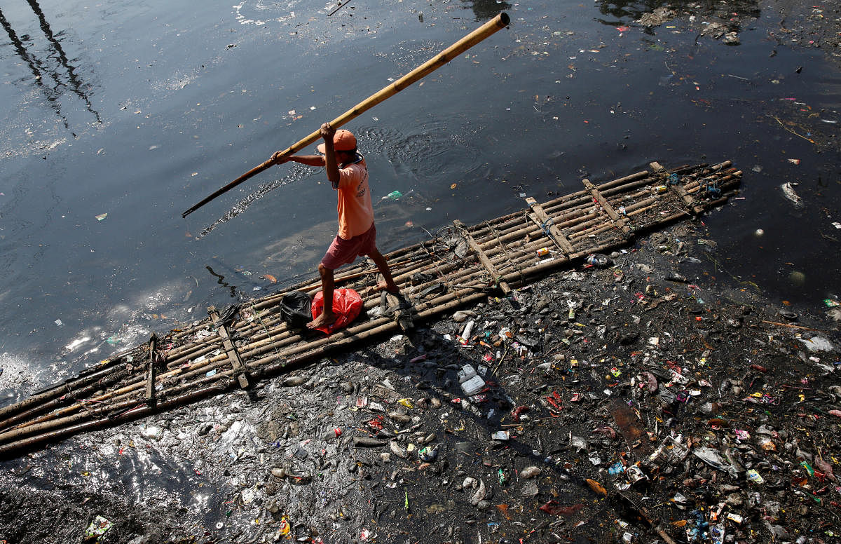 A government worker uses a raft to gather plastic and other debris for collection and disposal from a river in Jakarta. Reuters file photo