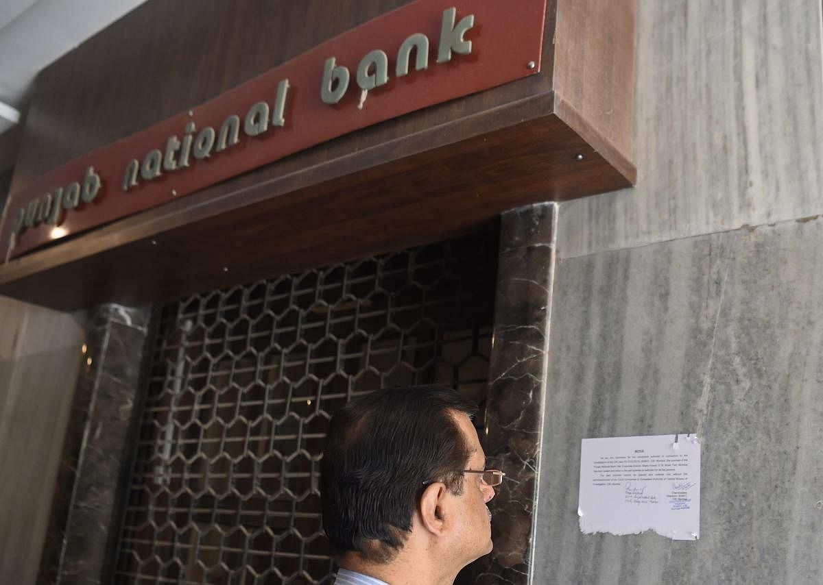 A man reads a notice by the Indian Central Bureau of Investigation (CBI) stating that the Brady House branch of the Punjab National Bank (PNB) has been sealed next to the entrance of the branch in Mumbai on February 19, 2018. Indian investigators have arrested three people who allegedly helped a billionaire jeweller obtain fake documents for overseas loans in one of the country's biggest bank scams, an official said February 17. / AFP PHOTO / INDRANIL MUKHERJEE