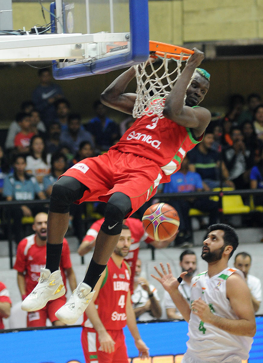 SWINGING STAR Ater Majok of Lebanon hangs on to the ring after scoring in the FIBA World Cup Asian qualifier basketball match in Bengaluru on Monday. DH Photo/ Srikanta Sharma R