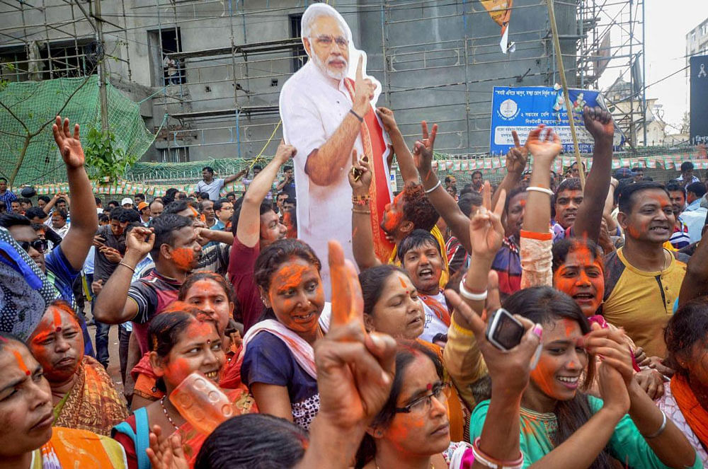 BJP supporters hold up a placard of Prime Minister Narendra Modi after party's victory in Tripura Assembly elections results in Agartala on Saturday. BJP's win marks an end to 25 years of CPI-M government rule in the state. PTI Photo.