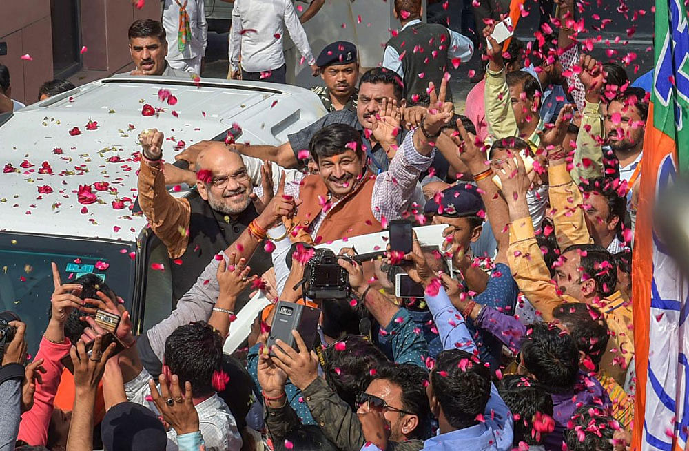 BJP President Amit Shah flashes victory sign as he is accorded welcome by party workers as they celebrate outside party headquarters after North-East states Assembly election results, in New Delhi on Saturday. PTI Photo