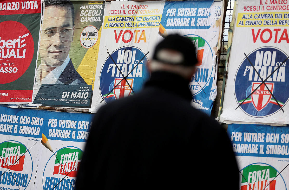 A man stands to look at electoral posters in Pomigliano D'Arco, near Naples, Italy. REUTERS