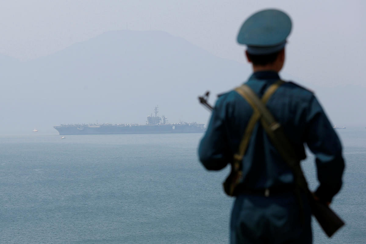 A Vietnamese soldier keeps watch in front of US aircraft carrier USS Carl Vinson after its arrival at a port in Danang, Vietnam, on Monday. REUTERS