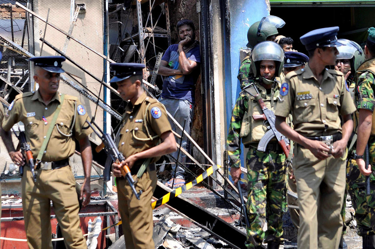 Sri Lanka's Special Task Force and police officers stand guard near a burnt house after a clash between two communities in Digana, central district of Kandy, Sri Lanka. REUTERS