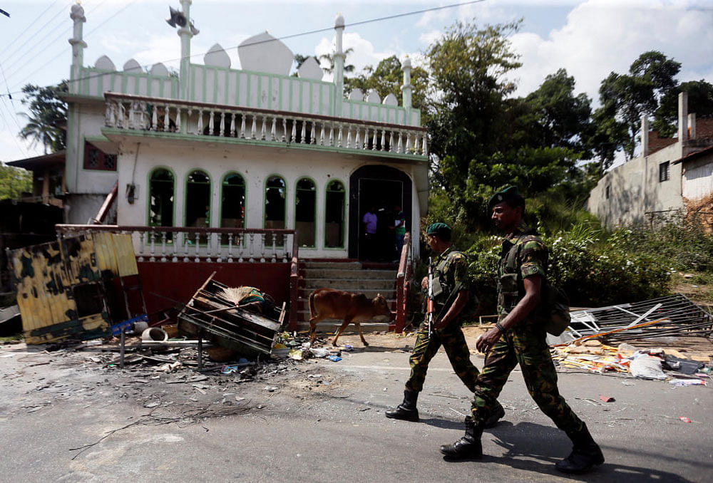 Sri Lanka's Special Task Force soldiers walk past a damaged mosque after a clash between two communities in Digana central district of Kandy. Reuters photo.