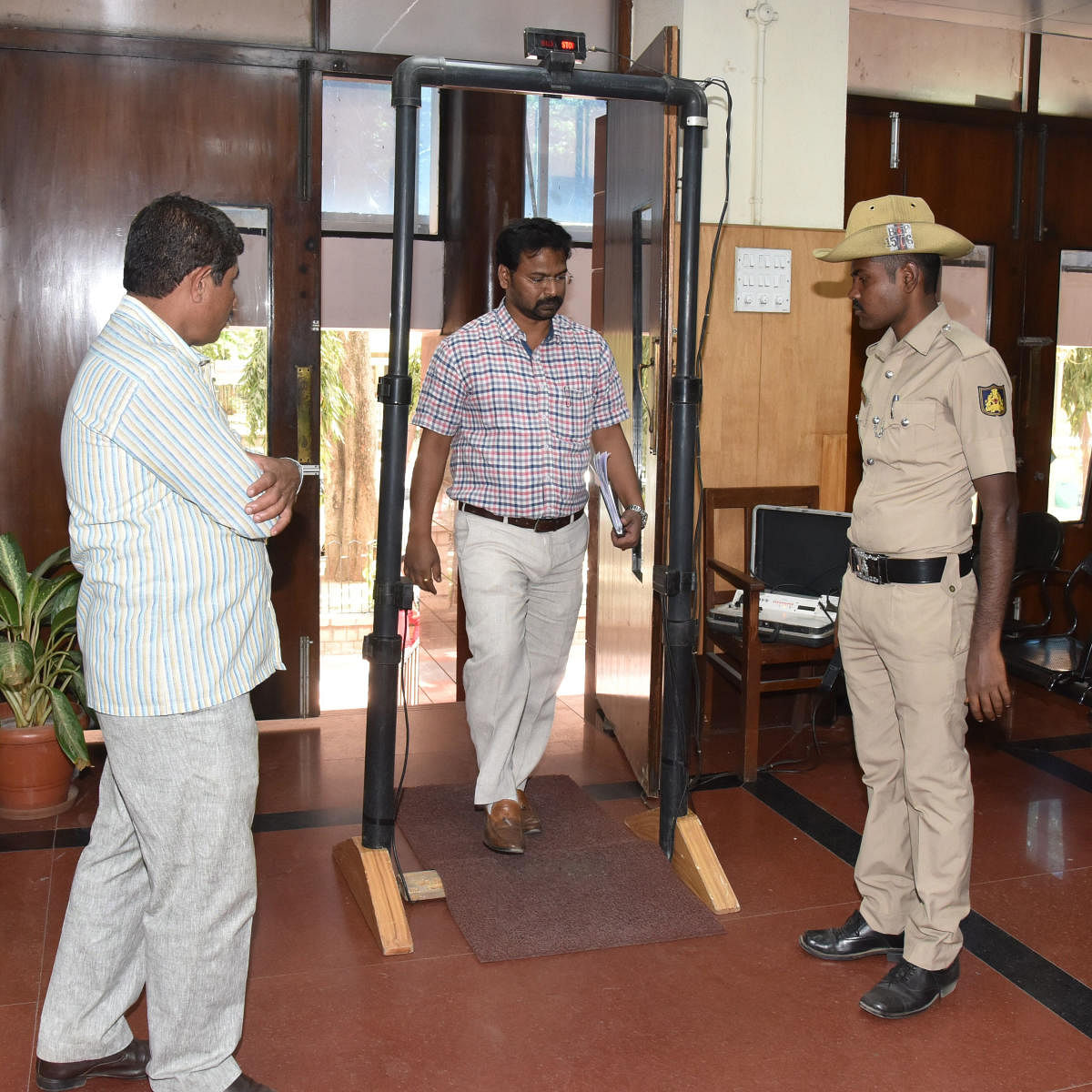 People enter the Lokayukta office at M S Building in Bengaluru through a new door frame metal detector that was installed on Thursday. DH Photo.