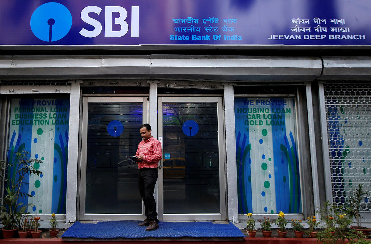 A man checks his mobile phones in front of State Bank of India (SBI) branch in Kolkata, India, February 9, 2018. REUTERS/Rupak De Chowdhuri