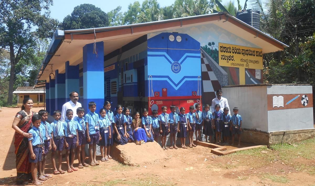 Students and staff of the Government Lower Primary School at Sannakere, Koppa taluk, pose for a photograph in front of the school building that resembles a train.