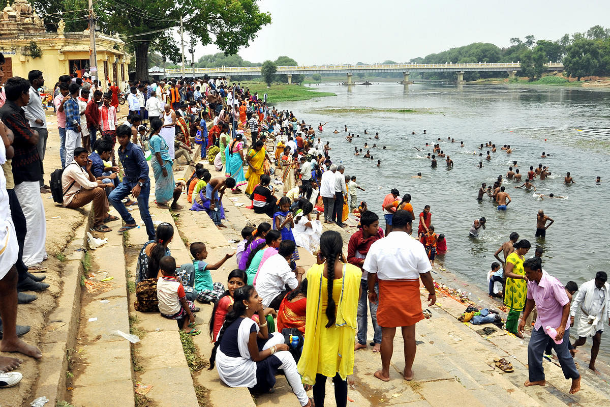 Devotees take a holy dip in River Kapila, at Nanjangud, on Wednesday. (Right) Members of voluntary organisations distribute water, juice and snacks to devotees, during the car festival. dh photos