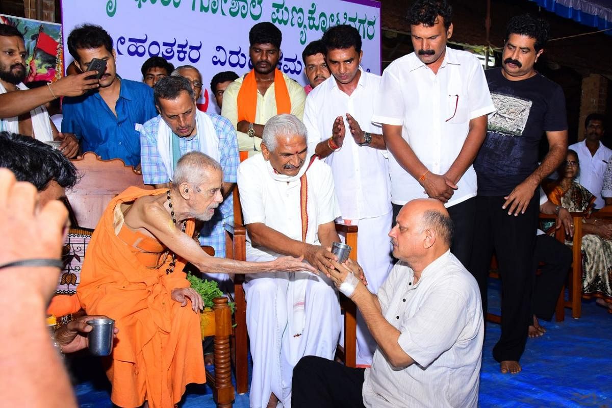 Pejawar seer Vishwesha Theertha Swami (left) offers milk to Amrithadhara Gaushala head Rajaram Bhat, who ended his fast-unto-death at Kairangala on Monday night.