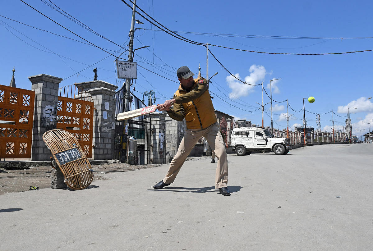 Indian police officer plays cricket on a deserted road during a strike called by Kashmiri separatists against the recent killings in Kashmir, in downtown Srinagar. PTI