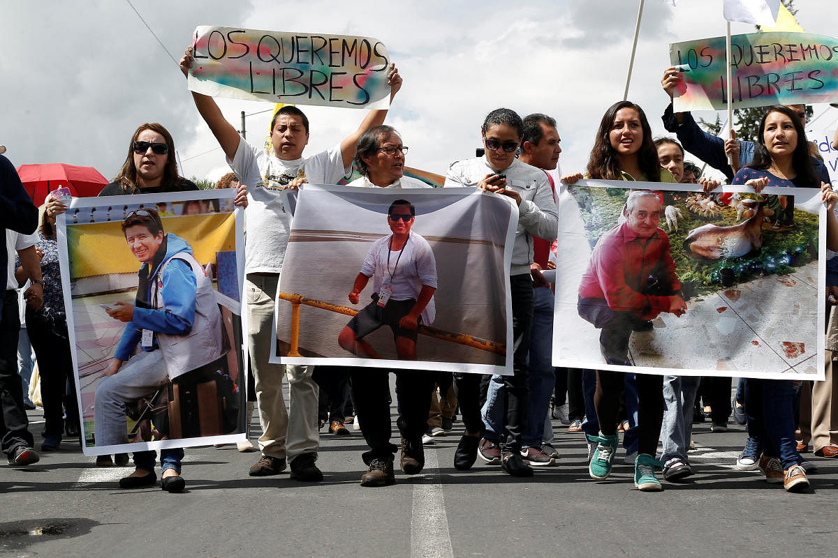 Relatives and friends hold pictures of Ecuadorean photojournalist Paul Rivas (L), journalist Javier Ortega (C) and their driver Efrain Segarra, who were kidnapped near the Colombian border, during a protest march to demand for their release, in Quito, Ecuador April 1, 2018. The sign at the back reads: 'We want them free.'