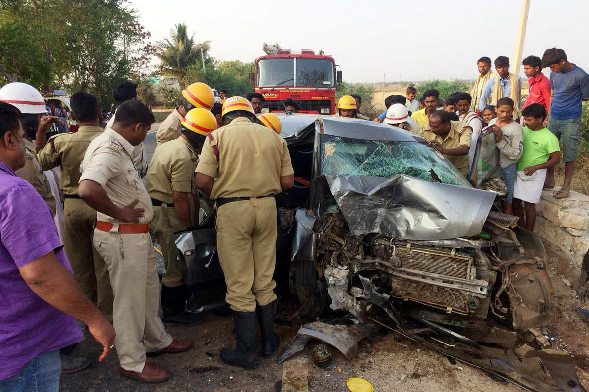 The personnel of fire and emergency services shift the mangled car, which crashed into a bridge on Srirangapatna-Bidar highway, near Kurugod in Ballari taluk in the early hours of Friday. DH Photo