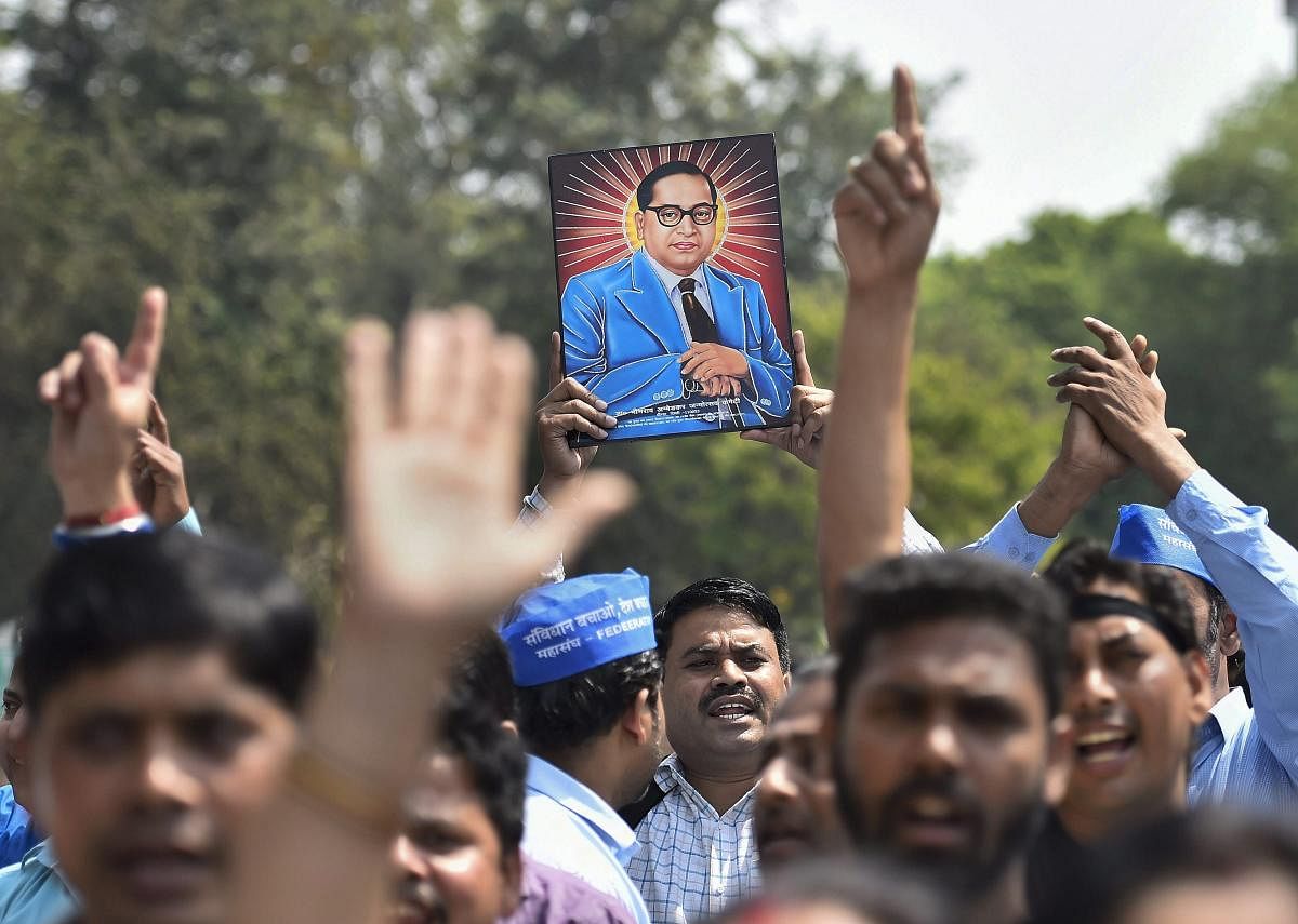 Members of Dalit community display a portrait of Bhim Rao Ambedkar during 'Bharat Bandh' against the alleged 'dilution' of Scheduled Castes / Scheduled Tribes act, in New Delhi, on Monday. (PTI Photo)