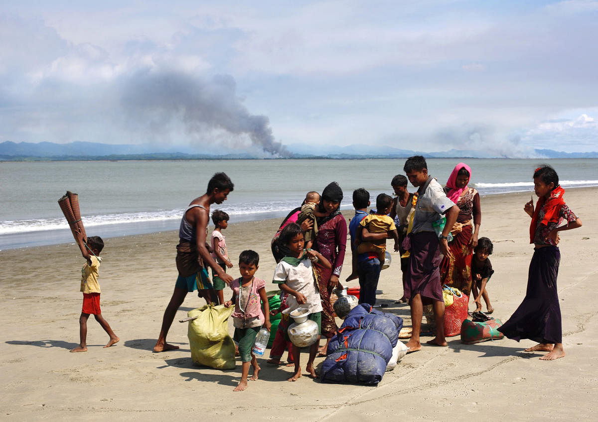 Smoke is seen on Myanmar's side of border as Rohingya refugees collect their belongings on a shore after crossing the Bangladesh-Myanmar border by boat through the Bay of Bengal in Shah Porir Dwip, Bangladesh. REUTERS FILE PHOTO