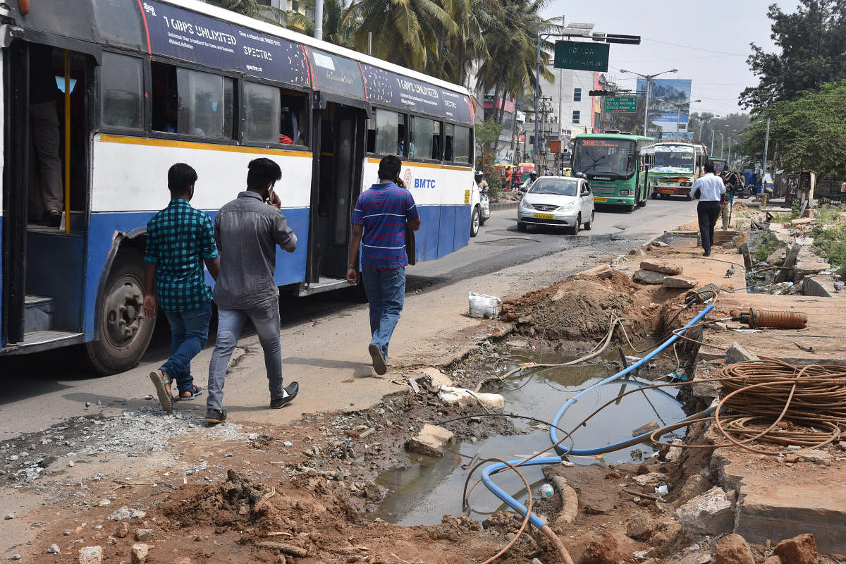 People struggle to walk due to no footpath and sewage water flow on road at Hulimavu gate, Bannerghatta Main Road in Bengaluru on Sunday. Photo by S K Dinesh