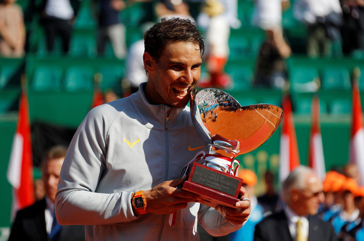 Rafael Nadal does his customary biting of the trophy after clinching the Monte Carlo Masters on Sunday. REUTERS