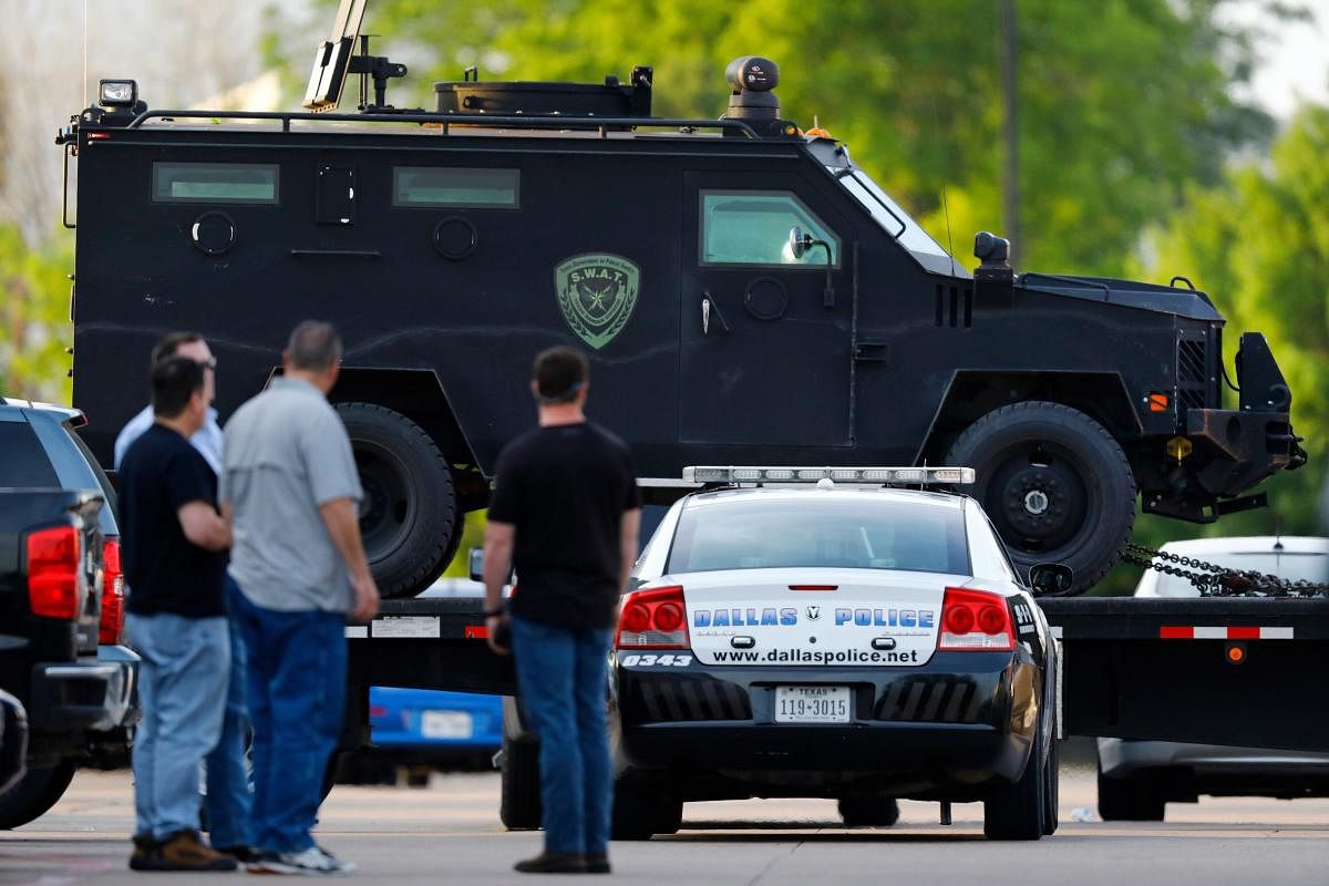 People watch as the Texas Department of Public Safety rolls in heavy duty vehicles to the Home Depot parking lot after two police officers and a civilian were shot by a man outside the home improvement store, on Tuesday in Dallas. AP/PTI