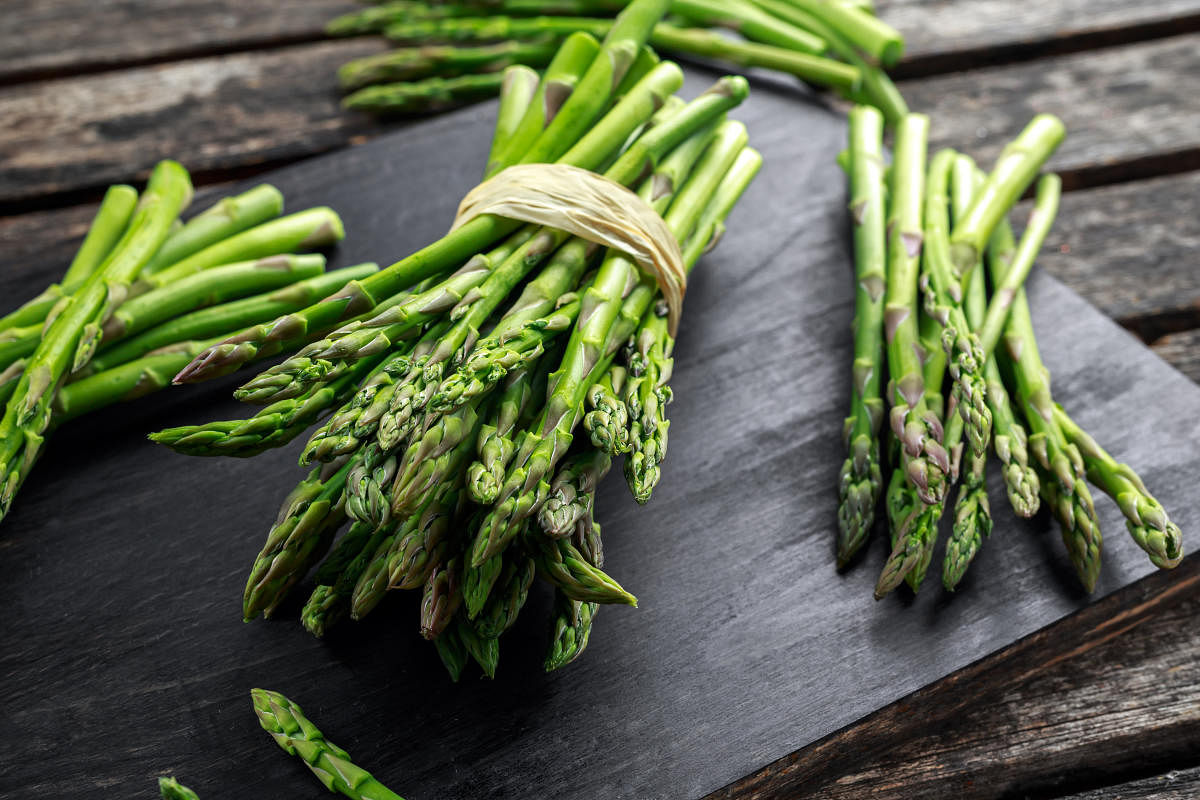 Fresh raw green Asparagus on wooden chopping board.