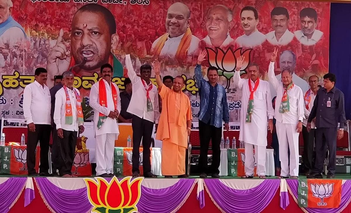 Uttar Pradesh Chief Minister Yogi Adityanath waves hand at crowd when he arrived on the stage for campaigning for the BJP at Vikasashram grounds in Sirsi on Thursday. DH Photo