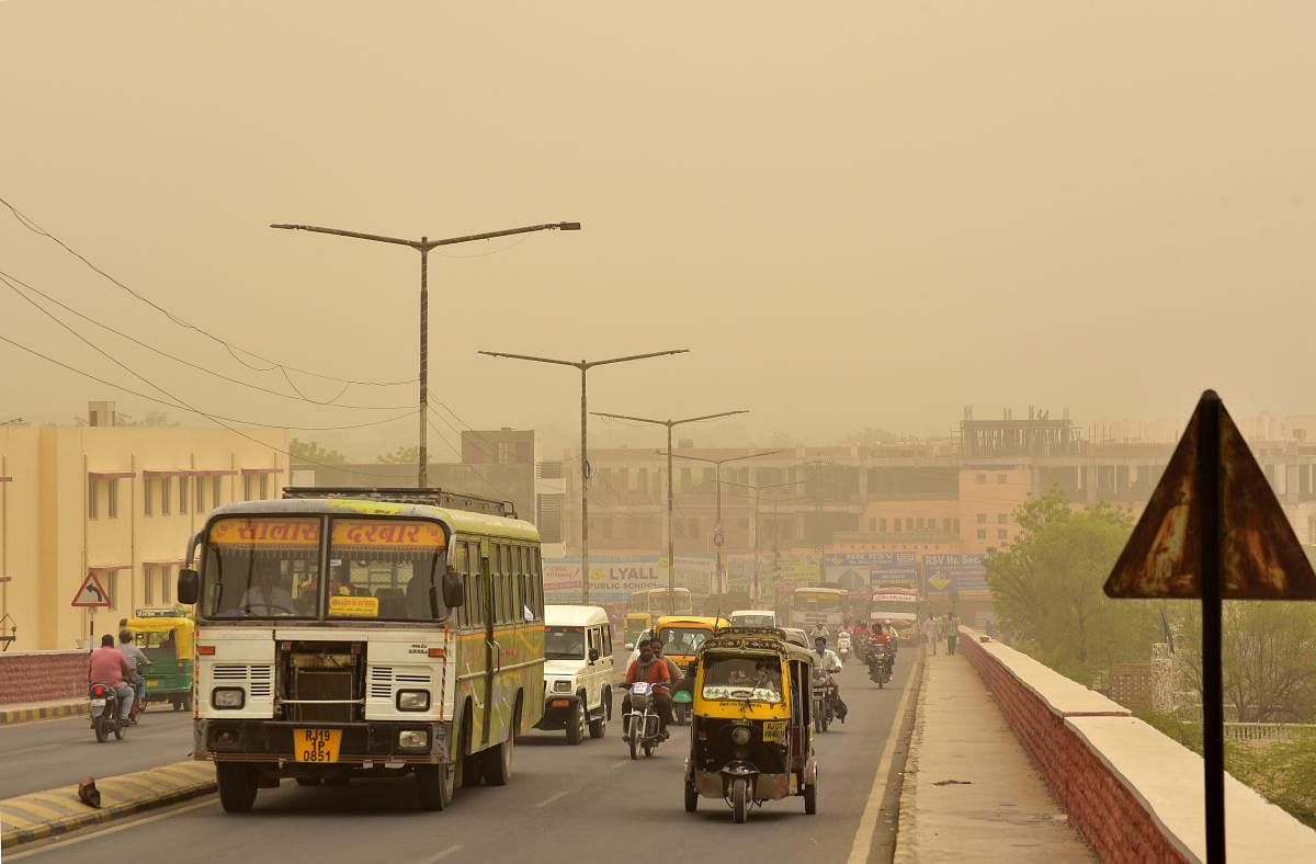 Vehicles ply on roads during a mild dust storm in Bikaner on Thursday. PTI