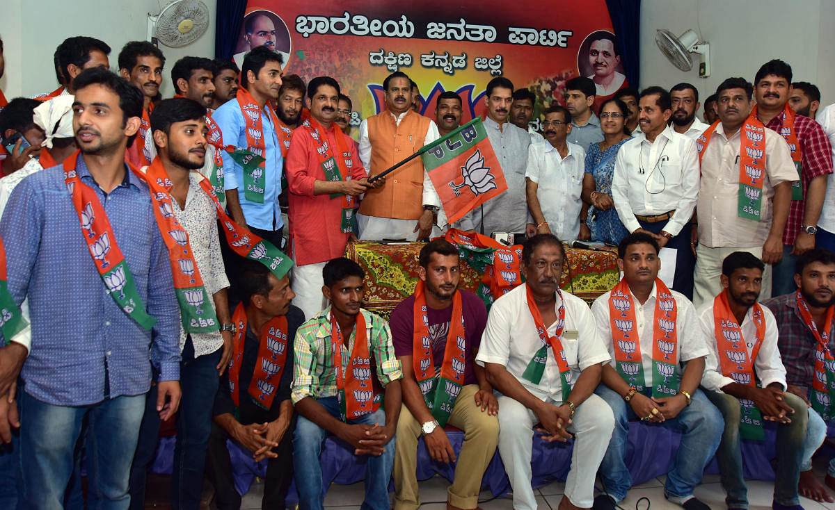 M P Nalin Kumar and Uttar Pradesh Rural Development Minister Dr Mahendra Singh Choudhary welcome Shashiraj Shetty and others to BJP by handing over party flags to them, at the district BJP office in Mangaluru on Thursday. DH Photo