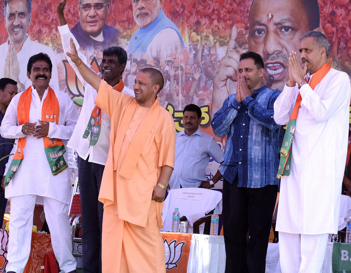 Uttar Pradesh Chief Minister Yogi Adityanath waves to the crowd at a rally at Sirsi, Uttara Kannada district on Thursday. Former minister Kota Srinivasa Poojary, Union Minister Anantkumar Hegde and party candidate Vishveshwar Hegde Kageri look on. dh phot