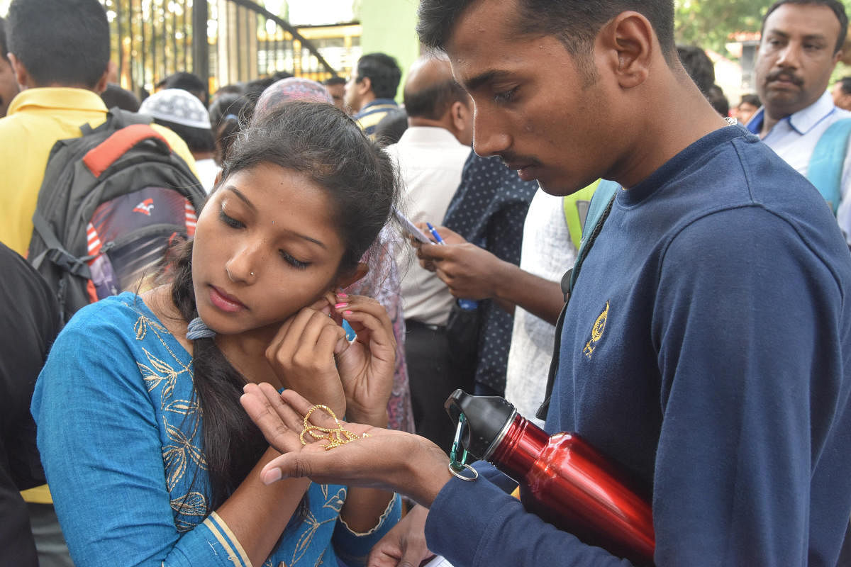 A student removes her jewellery before entering the hall for the National Eligibility Cum Entrance Test at an exam centre in the city on Sunday. DH Photo