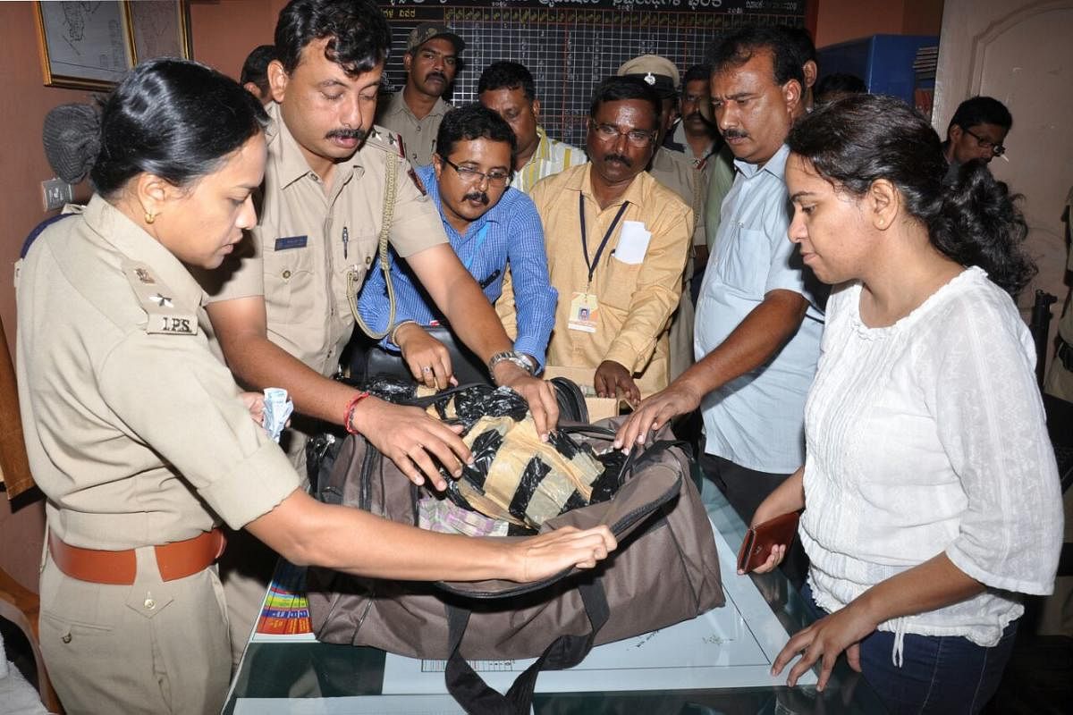 SP Divya Gopinath inspects a bag containing Rs 2.98 crore unaccounted cash seized from a private bus near Kythasandra during wee hours of Monday. DH Photo