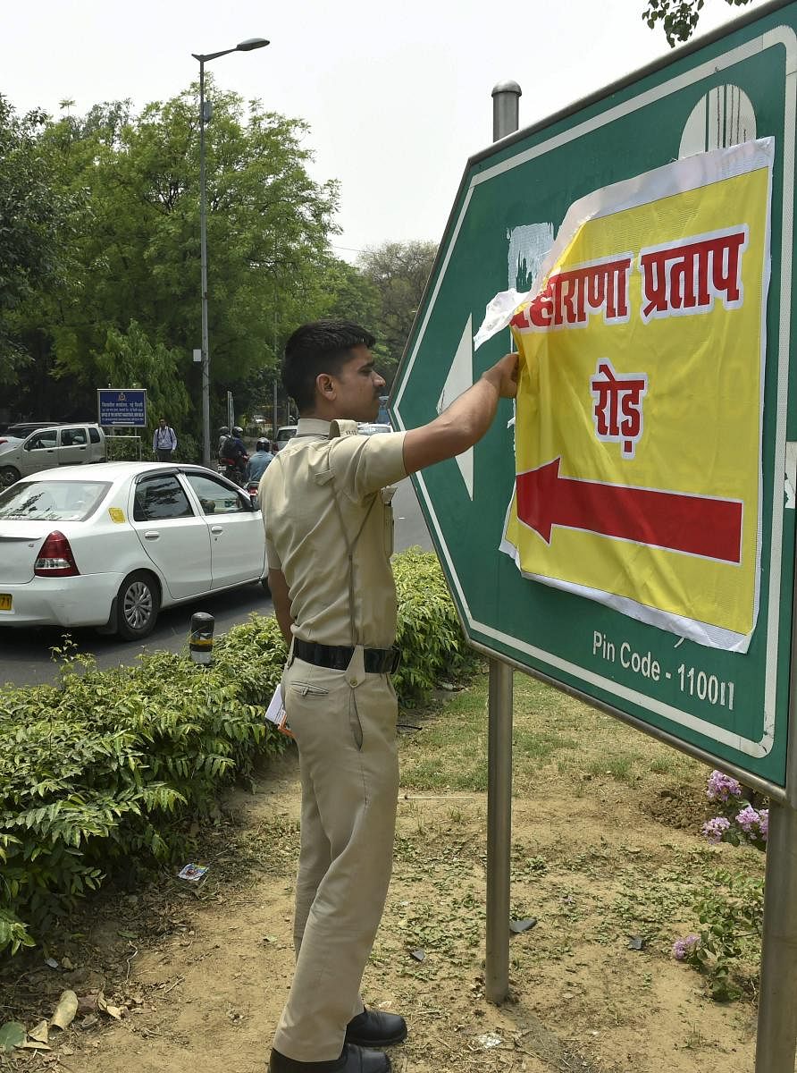 A Delhi policeman removes a poster bearing the name of Maharana Pratap that was pasted on Akbar Road signboard, in central Delhi, on Wednesday. PTI