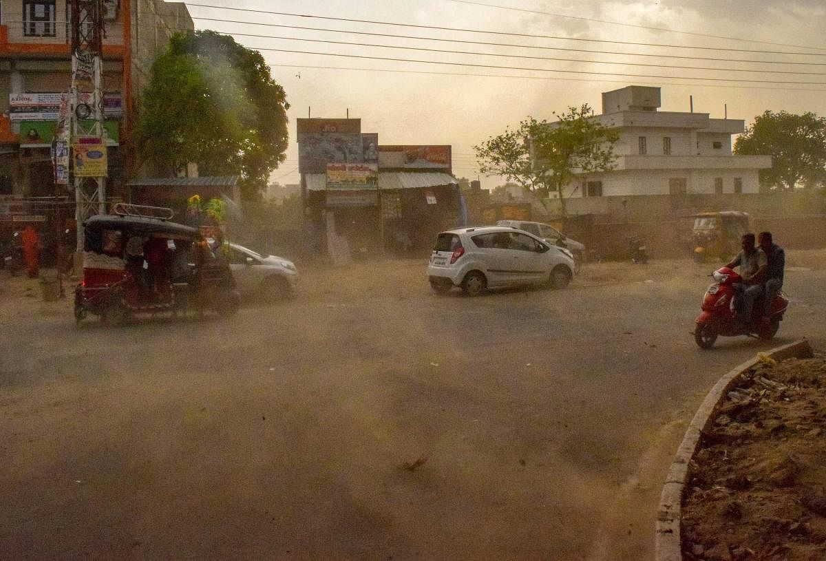 Vehicles ride past during a dust storm in Mathura on Wednesday. PTI