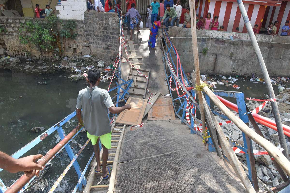 Metal foot bridge is clopped during a party workers going on for assembly election campaign on Tuesday, at ISRO colony, Cambridge layout, Sai Baba Temple road, Halasuru in Bengaluru on Wednesday. Photo by S K Dinesh