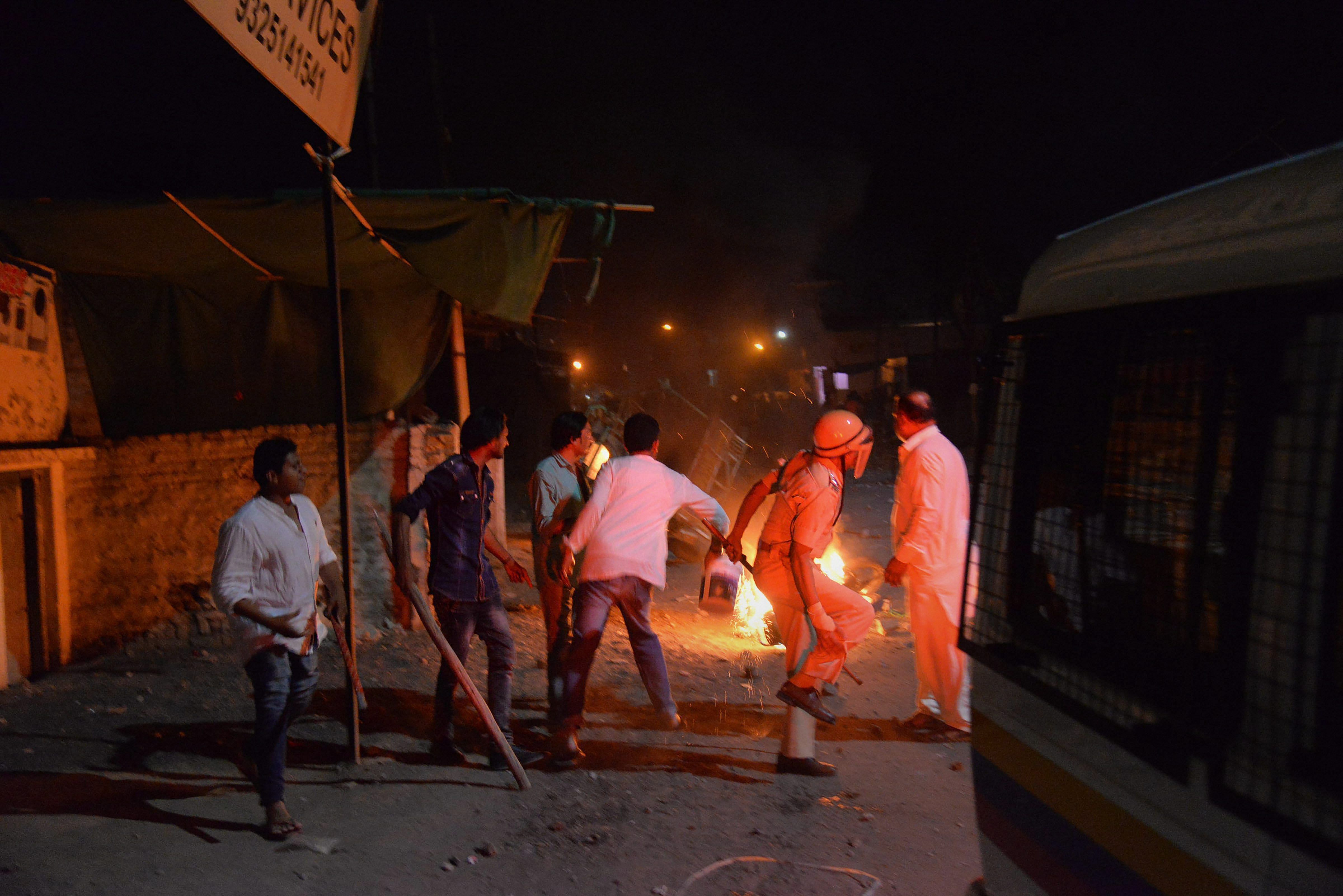 A police personnel looks as fire is set ablaze due to a communal riot that escalated due to clamping illegal water connection in a religious place in Moti Karanja area of Aurangabad on Friday. PTI